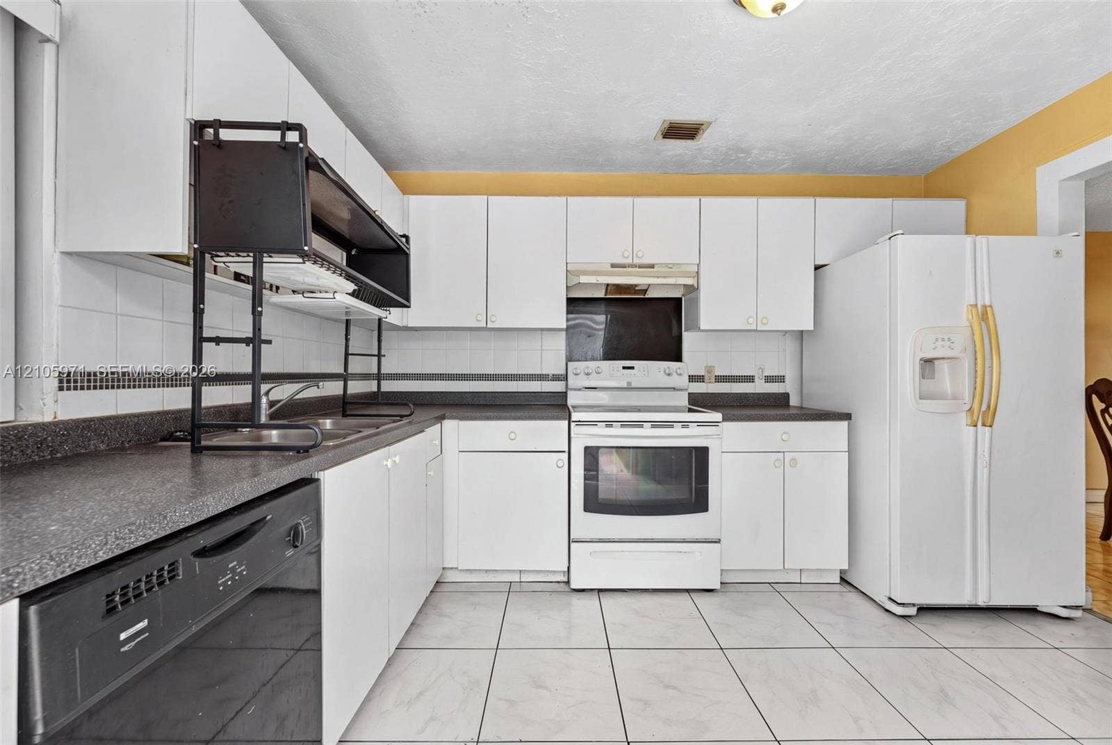 6604 Coconut Drive, Miramar, FL 33023 Kitchen featuring white cabinetry, dark countertops with tiled backsplash, white appliances, and large-format tile flooring