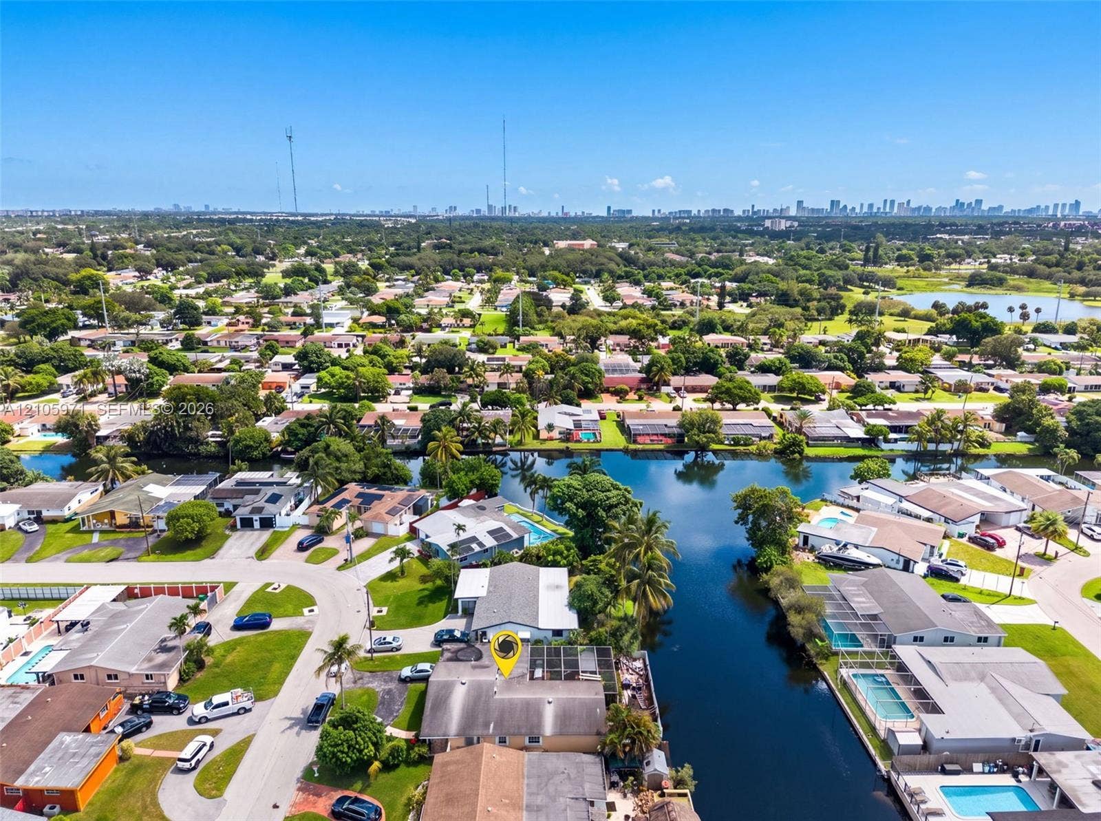 6604 Coconut Drive, Miramar, FL 33023 Aerial perspective featuring a waterfront property with direct canal access, mature palm trees, and an expansive skyline backdrop