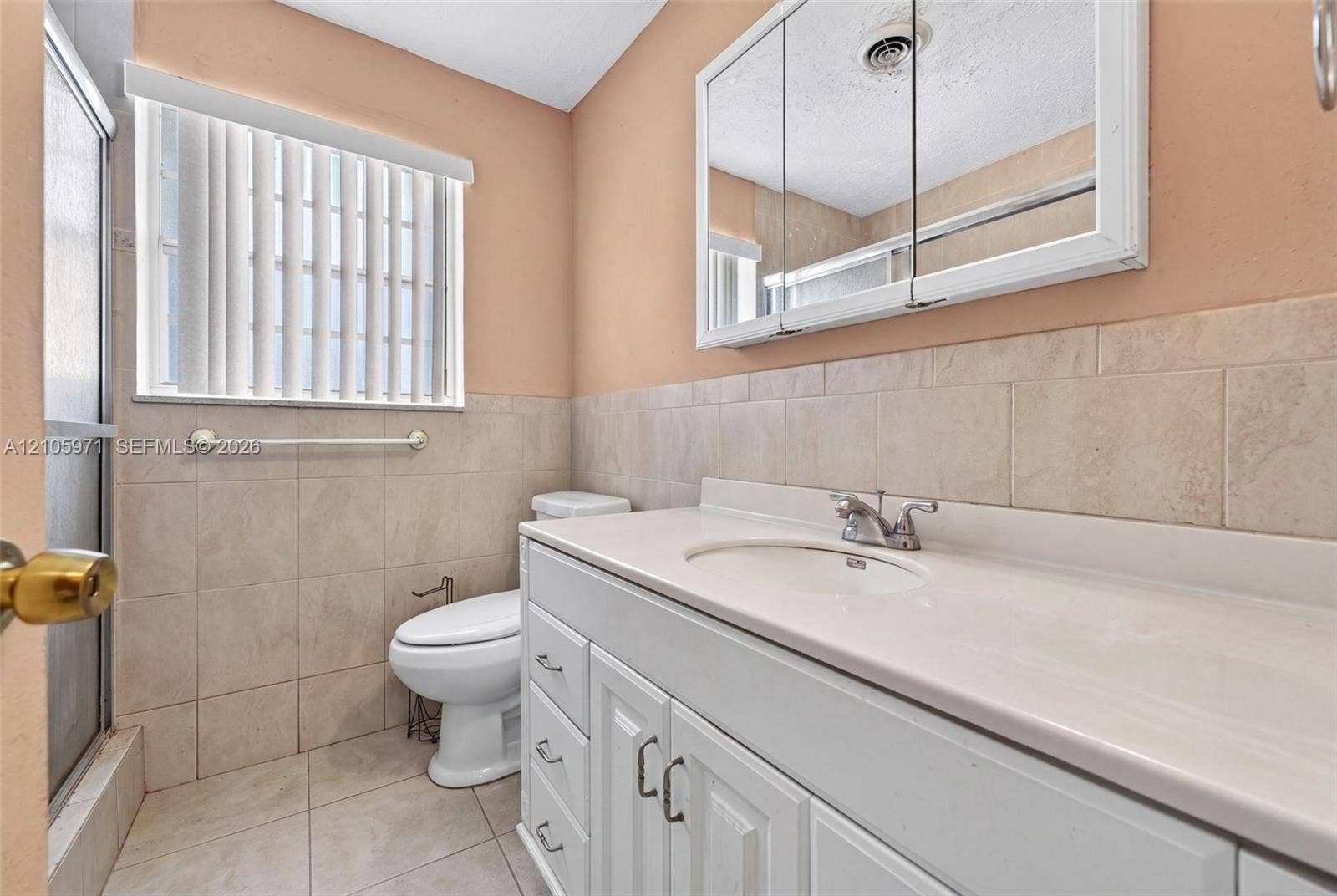 6604 Coconut Drive, Miramar, FL 33023 Bathroom featuring a white vanity with an integrated countertop, recessed medicine cabinet, neutral wall tile, and ceramic tile flooring