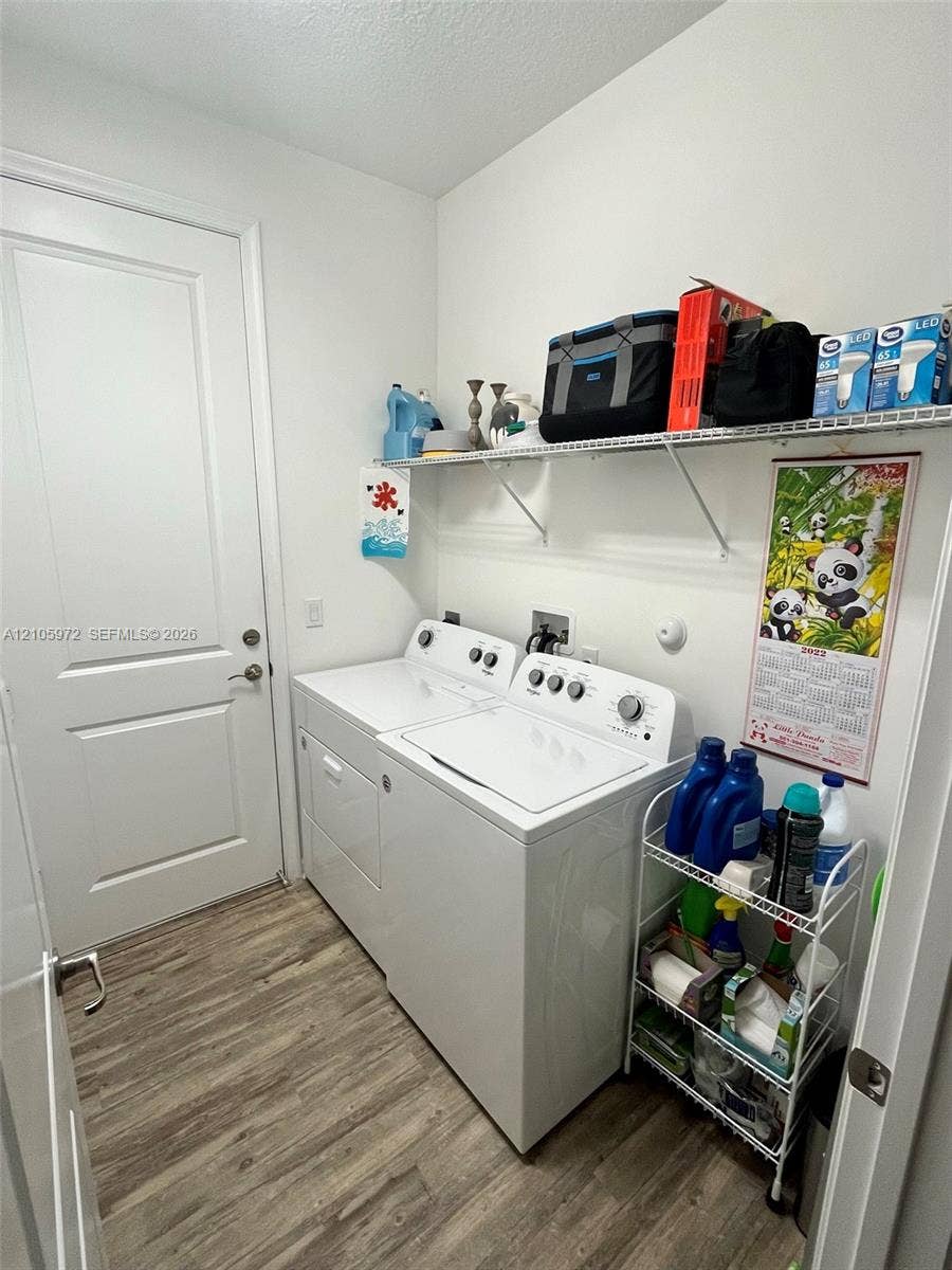6220 Oceanaire Way, Lake Worth, FL 33467 Laundry area featuring wood-finish flooring, a solid-core interior door, and overhead wire shelving