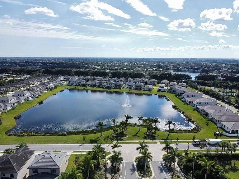 6220 Oceanaire Way, Lake Worth, FL 33467 Aerial perspective of a master-planned community featuring a central lake with a fountain, paved street network, manicured landscaping, and mature palm trees