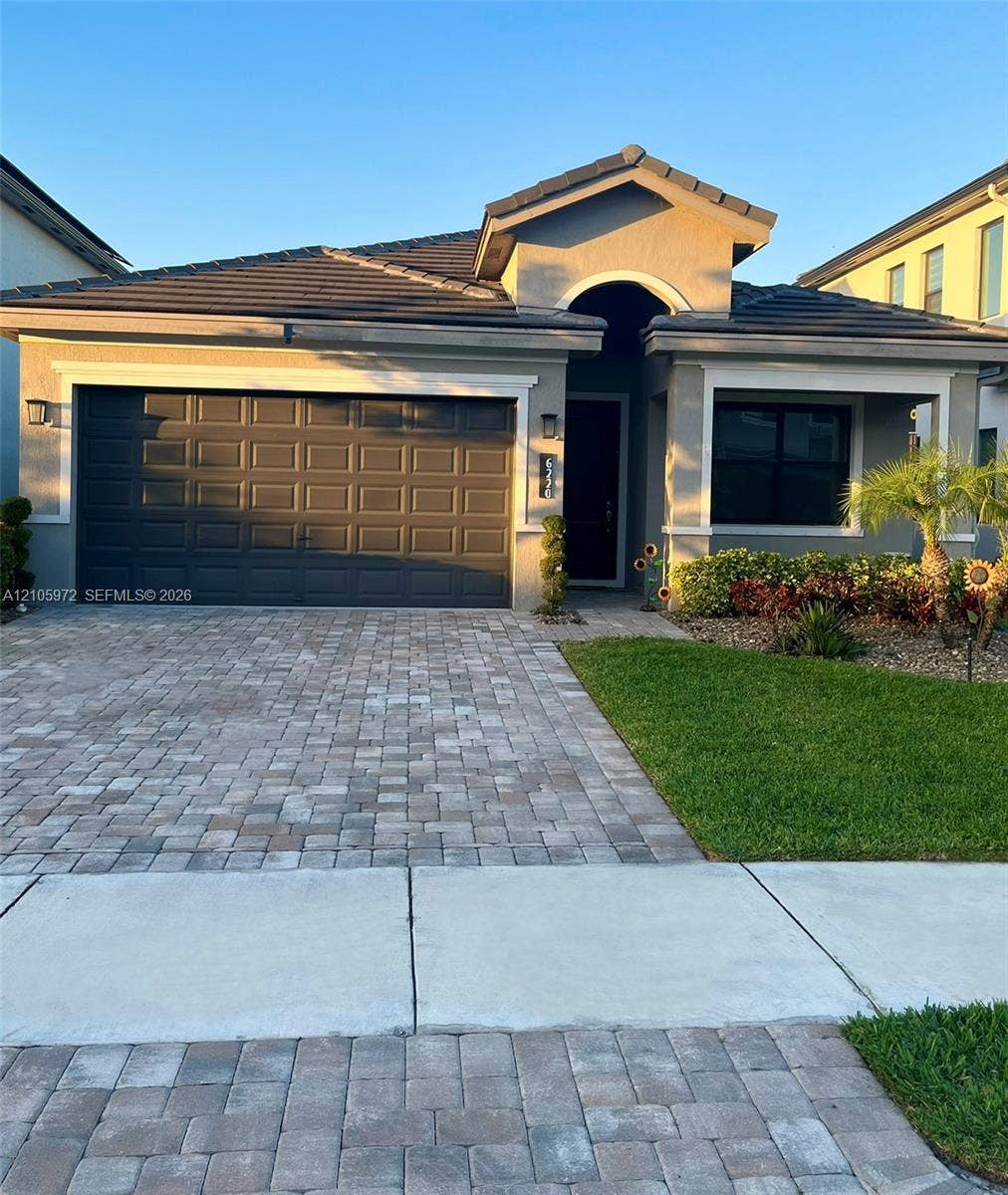 6220 Oceanaire Way, Lake Worth, FL 33467 Single-story residence featuring a tile roof, stucco exterior, paver driveway, and a two-car garage
