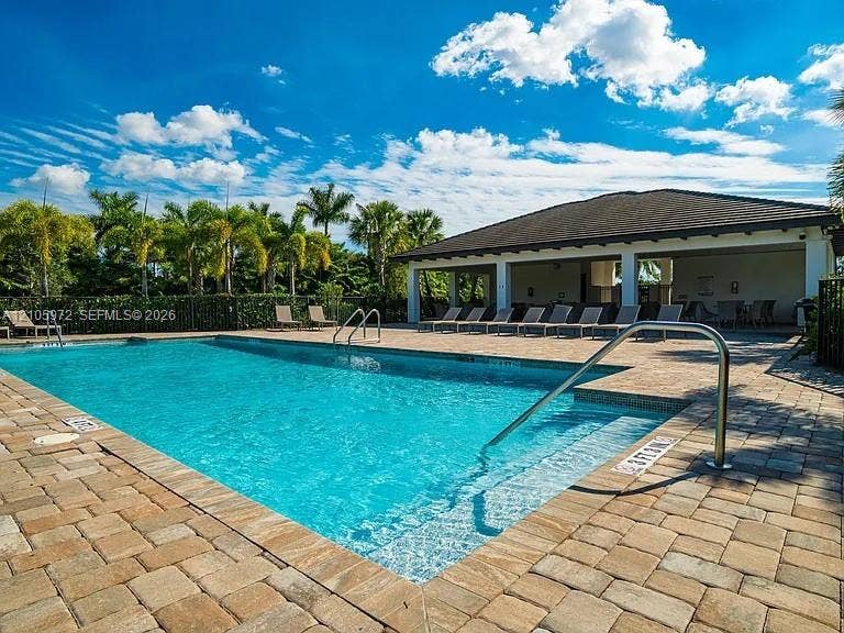 6220 Oceanaire Way, Lake Worth, FL 33467 In-ground swimming pool with a stone paver deck, stainless steel handrails, integrated steps, and a covered lanai