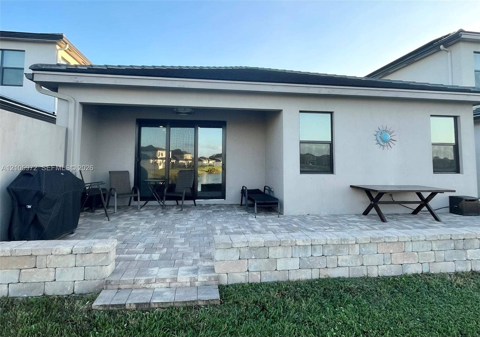6220 Oceanaire Way, Lake Worth, FL 33467 Covered concrete patio featuring pavers, a decorative block retaining wall, and sliding glass door access
