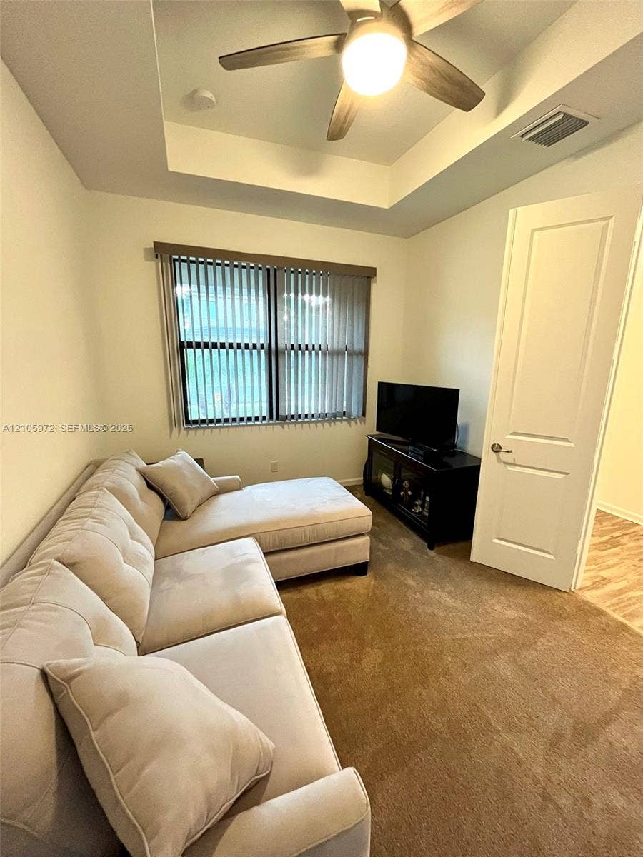 6220 Oceanaire Way, Lake Worth, FL 33467 Tray ceiling featuring a central lighted ceiling fan, carpeted flooring, and a single-panel interior door