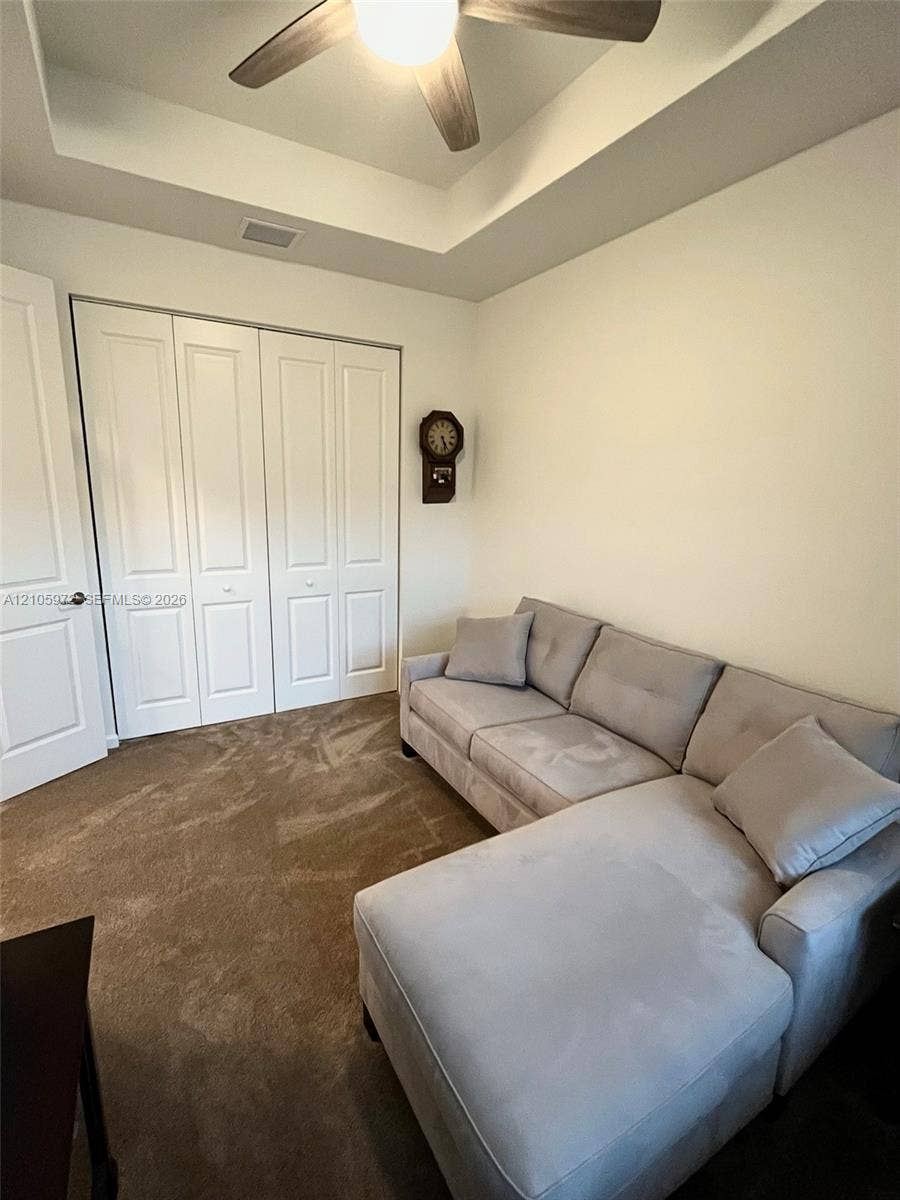 6220 Oceanaire Way, Lake Worth, FL 33467 Tray ceiling with a central multi-blade ceiling fan, wall-to-wall carpeted flooring, and white paneled bi-fold closet doors