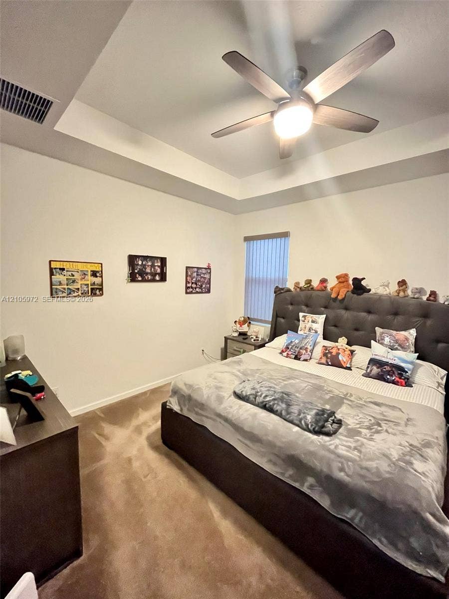 6220 Oceanaire Way, Lake Worth, FL 33467 Tray ceiling featuring a central five-blade ceiling fan with integrated lighting and carpeted flooring
