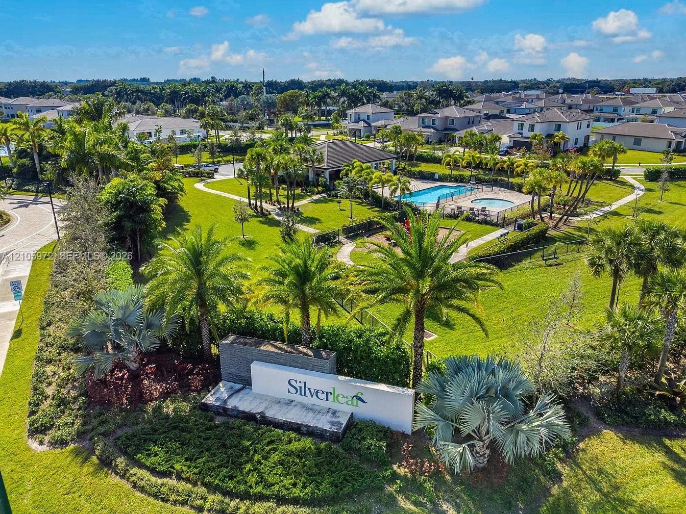 6220 Oceanaire Way, Lake Worth, FL 33467 Aerial view of community grounds featuring a swimming pool, spa, playground, landscaped green spaces, and palm tree-lined walkways
