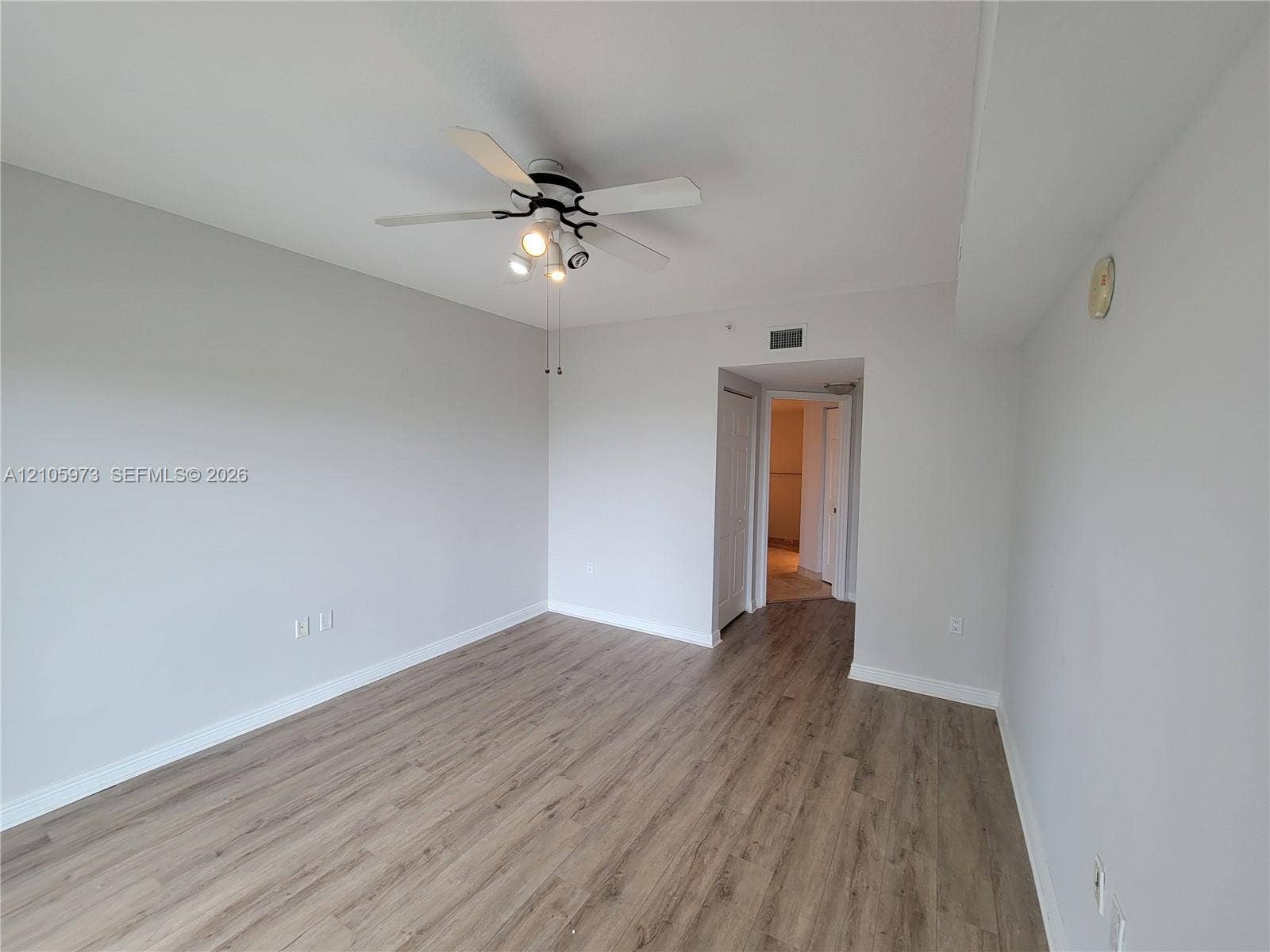 1755 E Hallandale Beach Boulevard, #704E, Hallandale Beach, Hallandale Beach, FL 33009 Neutral interior space featuring wood-finish flooring, a ceiling fan with integrated lighting, and a six-panel interior door