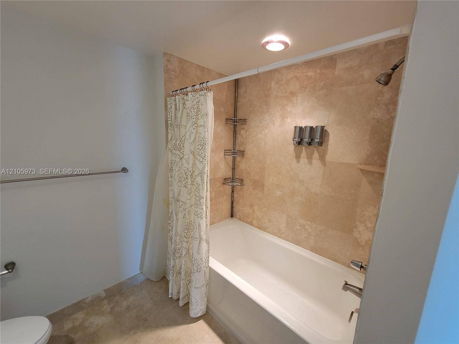 1755 E Hallandale Beach Boulevard, #704E, Hallandale Beach, Hallandale Beach, FL 33009 Bathtub with full-height stone tile surround, integrated metal shelving, wall-mounted shower head, and recessed lighting