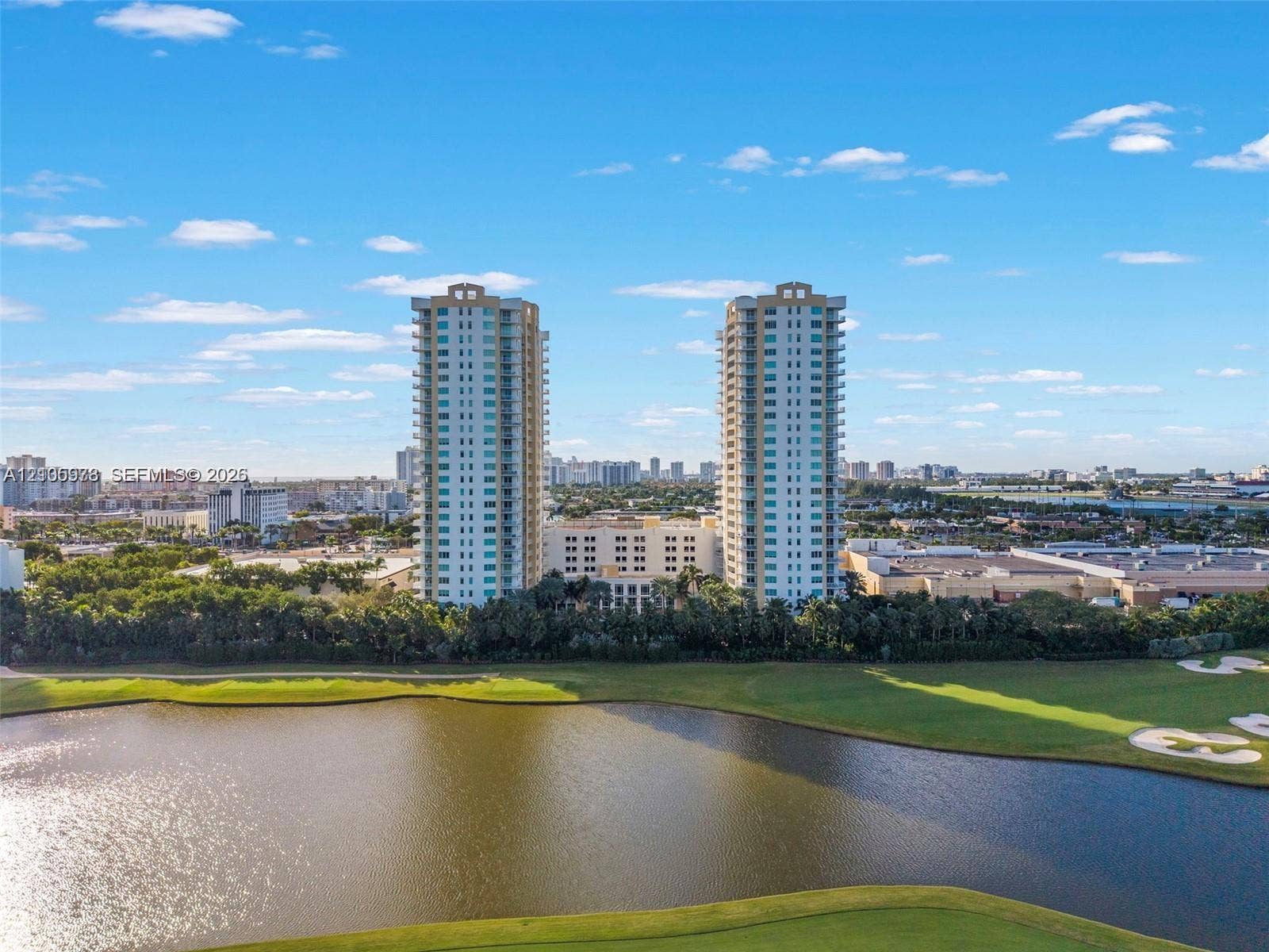 1755 E Hallandale Beach Boulevard, #704E, Hallandale Beach, Hallandale Beach, FL 33009 High-rise towers featuring wraparound balconies and glass-panel railing, situated alongside a water feature and landscaped grounds
