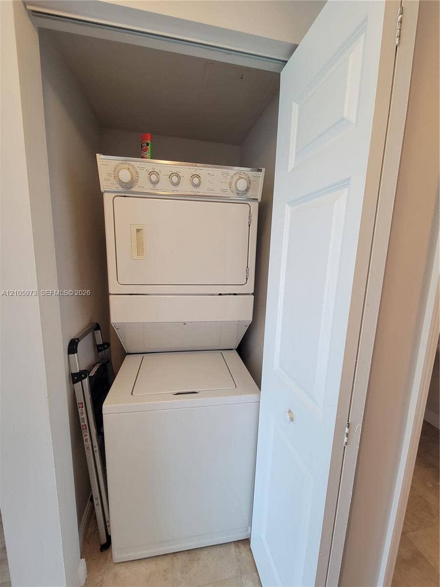 1755 E Hallandale Beach Boulevard, #704E, Hallandale Beach, Hallandale Beach, FL 33009 Stacked white washer and dryer unit housed within a dedicated laundry closet featuring a bi-fold door