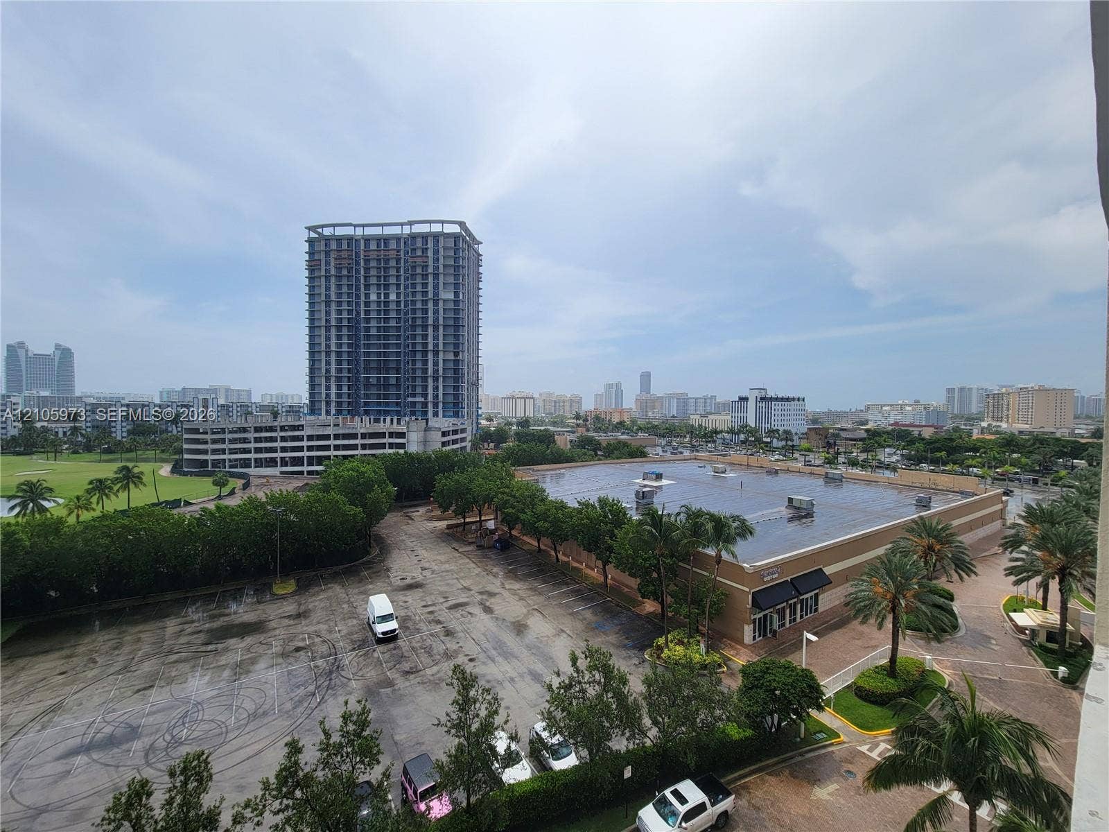 1755 E Hallandale Beach Boulevard, #704E, Hallandale Beach, Hallandale Beach, FL 33009 Elevated perspective featuring mature palm trees, paved parking areas, and a multi-story high-rise skyline