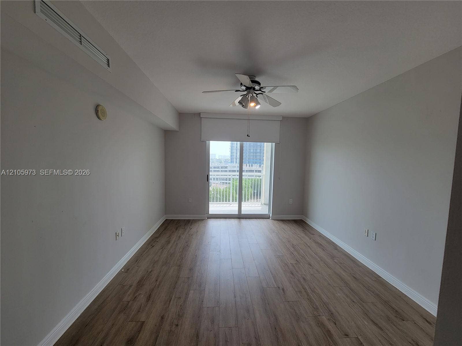 1755 E Hallandale Beach Boulevard, #704E, Hallandale Beach, Hallandale Beach, FL 33009 Living space featuring wood-finish flooring, a ceiling fan with integrated lighting, and sliding glass doors with access to an exterior balcony