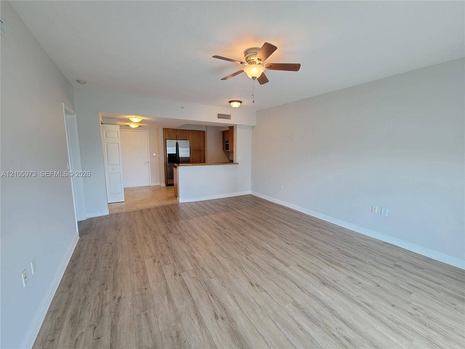 1755 E Hallandale Beach Boulevard, #704E, Hallandale Beach, Hallandale Beach, FL 33009 Open-concept interior featuring light wood-finish flooring, a ceiling fan with integrated lighting, and a kitchen pass-through counter
