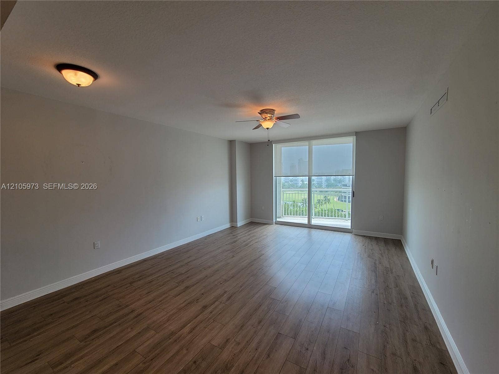 1755 E Hallandale Beach Boulevard, #704E, Hallandale Beach, Hallandale Beach, FL 33009 Open-concept room featuring wood-finish flooring, ceiling fan, flush-mount lighting, and large sliding glass door with access to a balcony