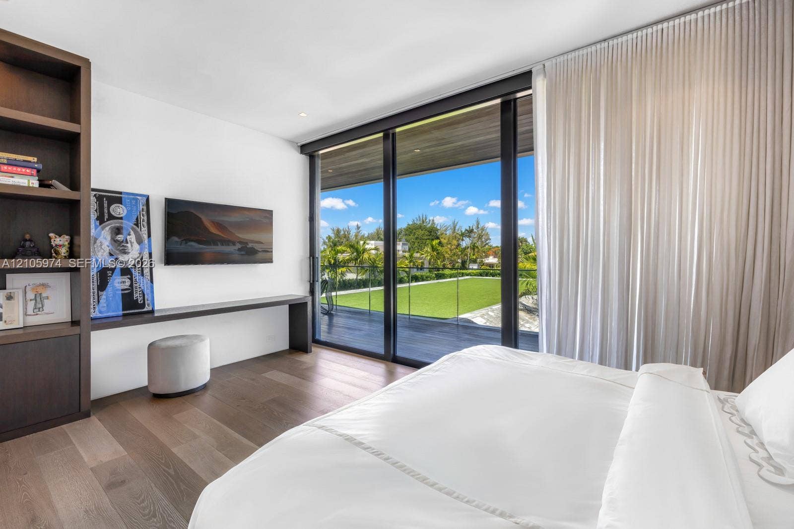 4395 Pine Tree Drive, Miami Beach, FL 33140 Floor-to-ceiling sliding glass doors, built-in floor-to-ceiling shelving, wood-finish flooring, and integrated wall-mounted desk