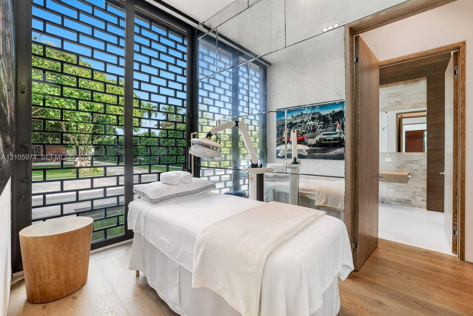 4395 Pine Tree Drive, Miami Beach, FL 33140 Floor-to-ceiling windows with black metal decorative screening, mirror-panel wall cladding, and wood-finish flooring
