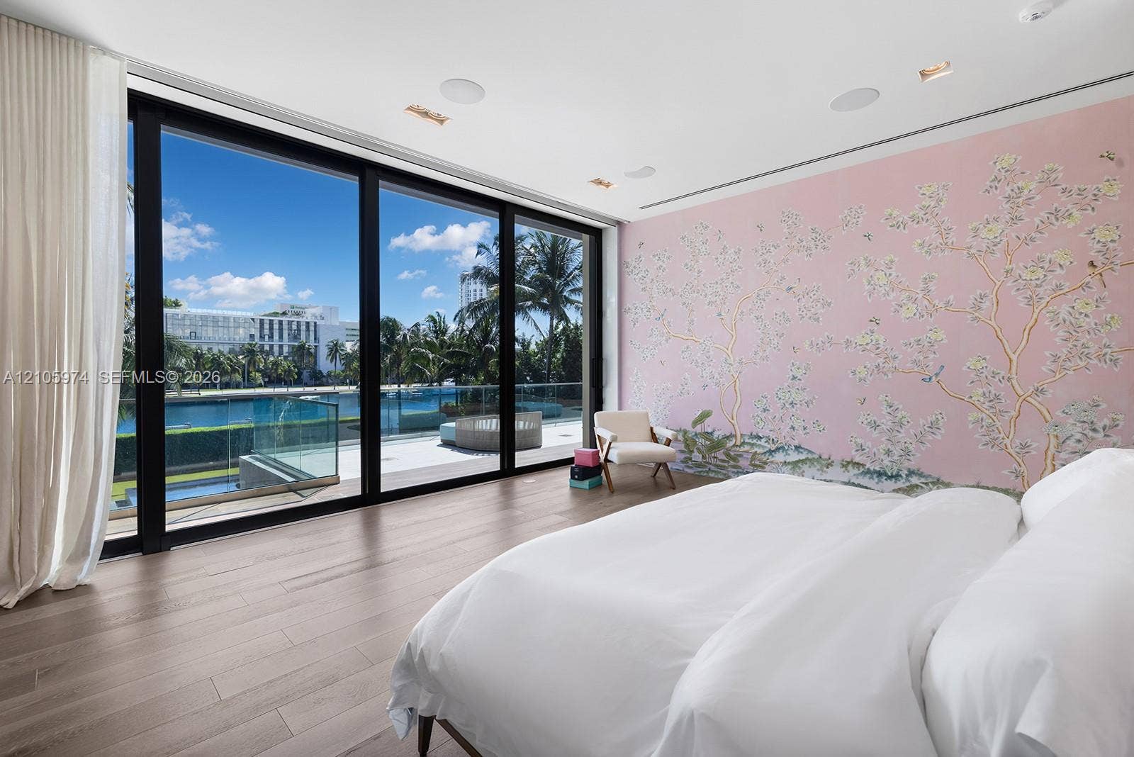 4395 Pine Tree Drive, Miami Beach, FL 33140 Floor-to-ceiling glass sliding doors, wood-finish flooring, recessed ceiling lighting, and custom floral-motif wall covering