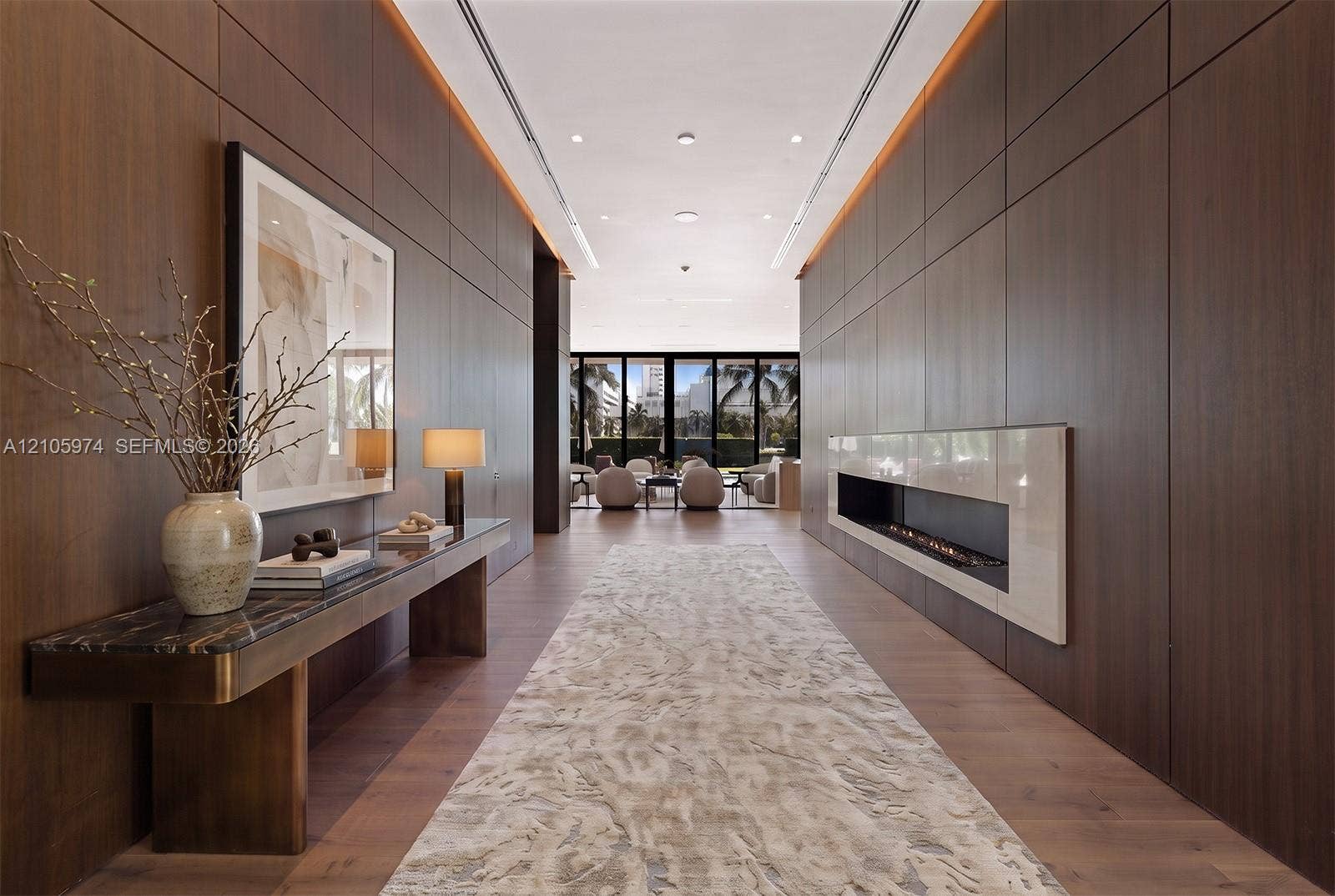 4395 Pine Tree Drive, Miami Beach, FL 33140 Entry hall featuring floor-to-ceiling wood paneling, recessed lighting, linear fireplace with a stone-surround, and wide-plank wood-finish flooring
