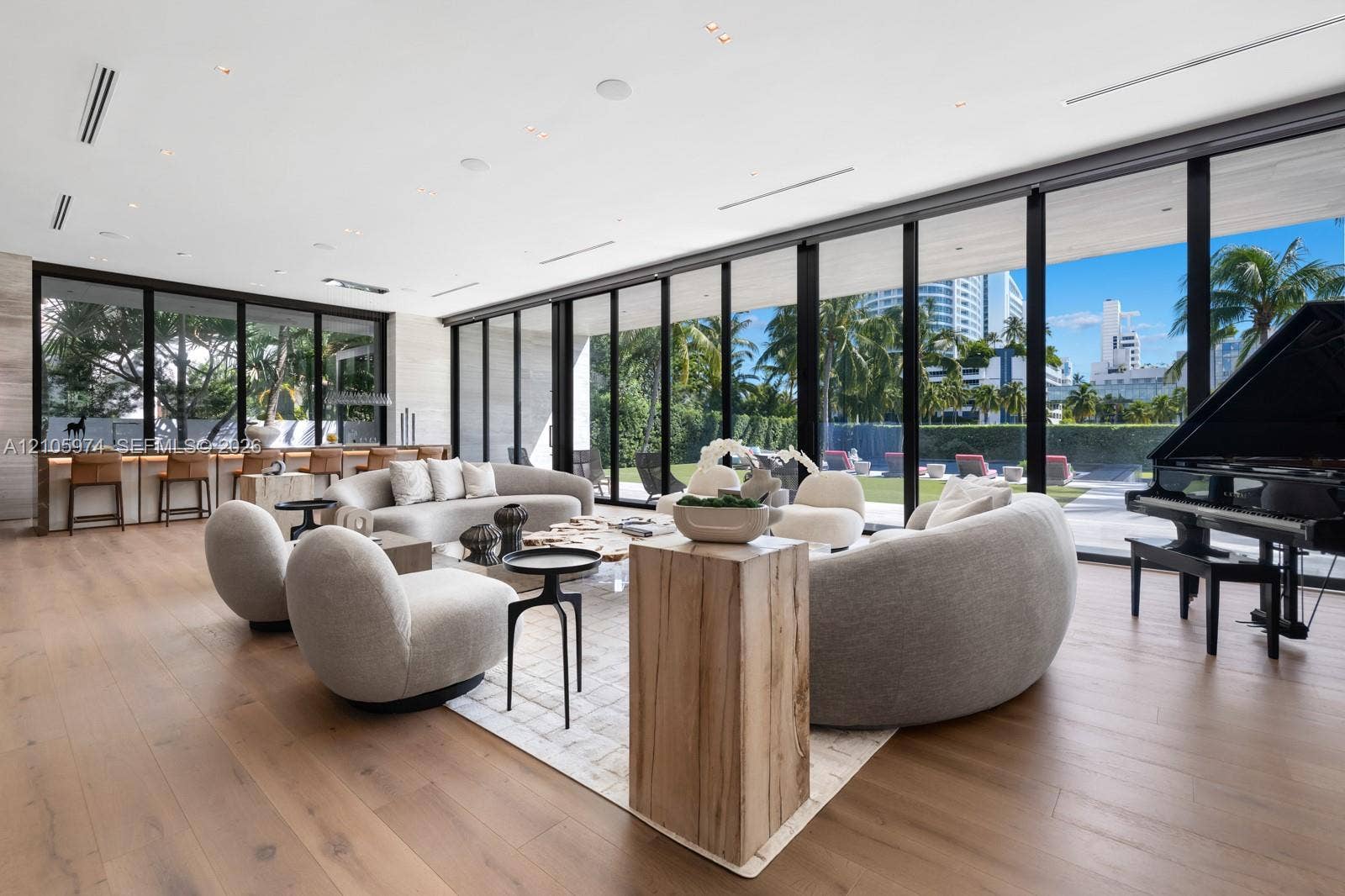 4395 Pine Tree Drive, Miami Beach, FL 33140 Floor-to-ceiling glass wall systems, wood-finish flooring, built-in wet bar, recessed ceiling lighting, and custom stone wall cladding