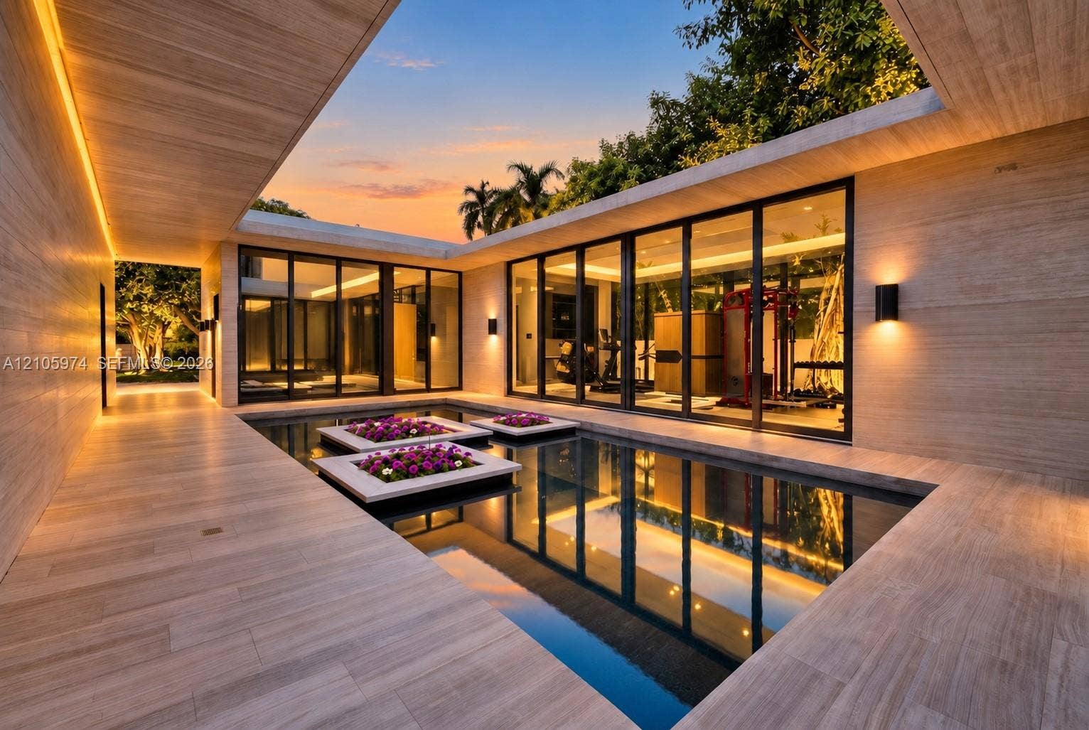 4395 Pine Tree Drive, Miami Beach, FL 33140 Central courtyard featuring a reflecting pool with integrated planters, floor-to-ceiling glass panel walls, natural stone-finish decking, and recessed perimeter lighting