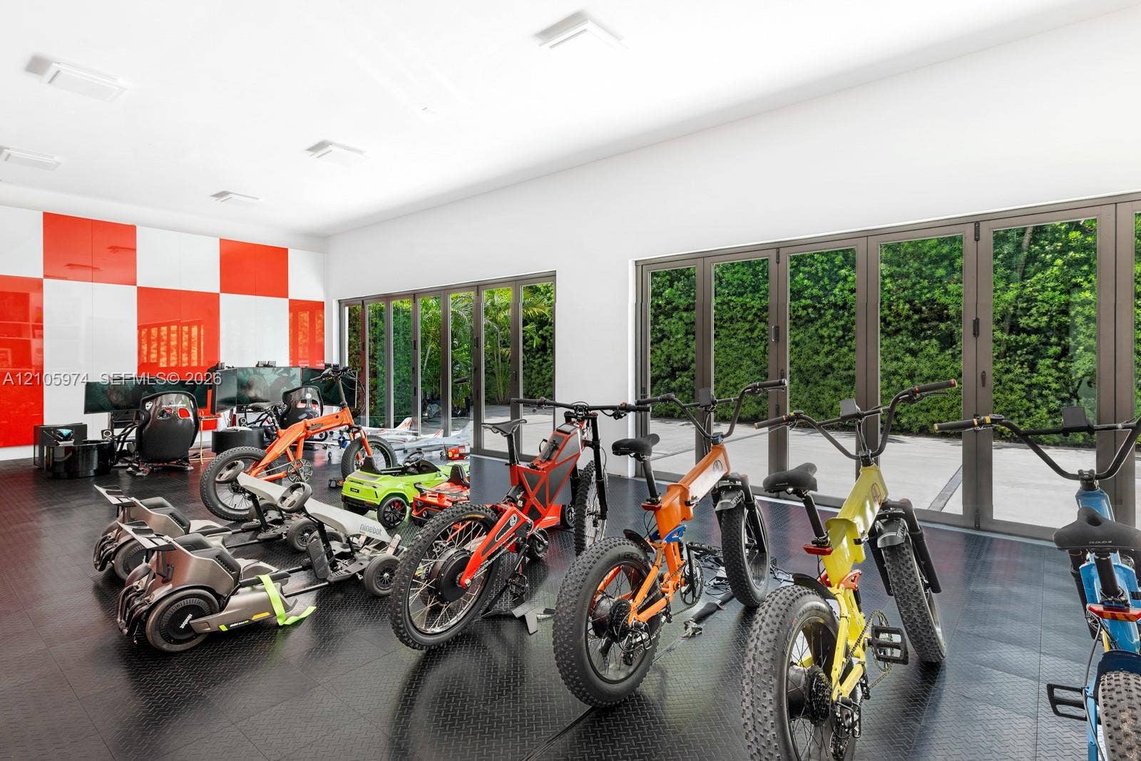 4395 Pine Tree Drive, Miami Beach, FL 33140 Expansive room featuring high-gloss red and white wall panels, durable rubberized diamond-plate flooring, and two sets of multi-panel aluminum-framed glass folding doors