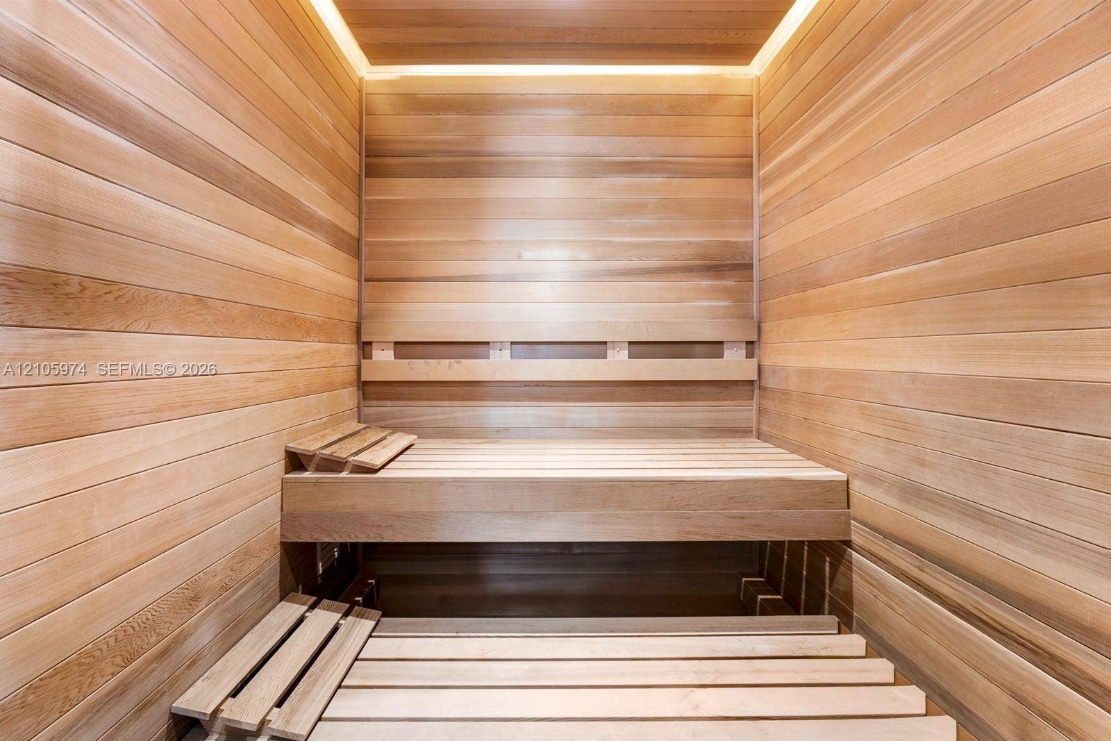 4395 Pine Tree Drive, Miami Beach, FL 33140 Sauna interior featuring natural wood wall paneling, tiered slatted benches, and recessed perimeter ceiling lighting