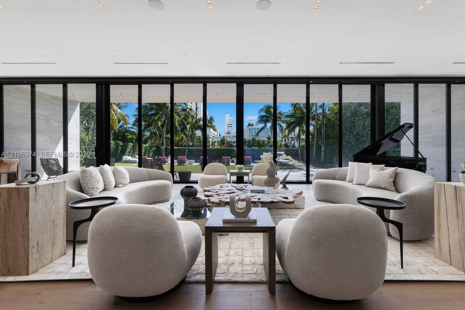 4395 Pine Tree Drive, Miami Beach, FL 33140 Floor-to-ceiling retractable glass walls, wide-plank wood-finish flooring, recessed ceiling lighting, and expansive stone-clad wall accents