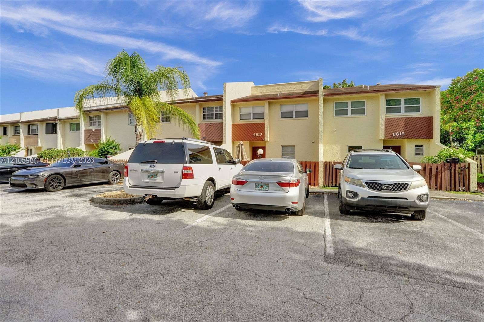 6813 NW 29th Avenue, Fort Lauderdale, Fort Lauderdale, FL 33309 Multi-unit exterior featuring a painted stucco finish, horizontal paneling accents, individual private entries, and paved surface parking