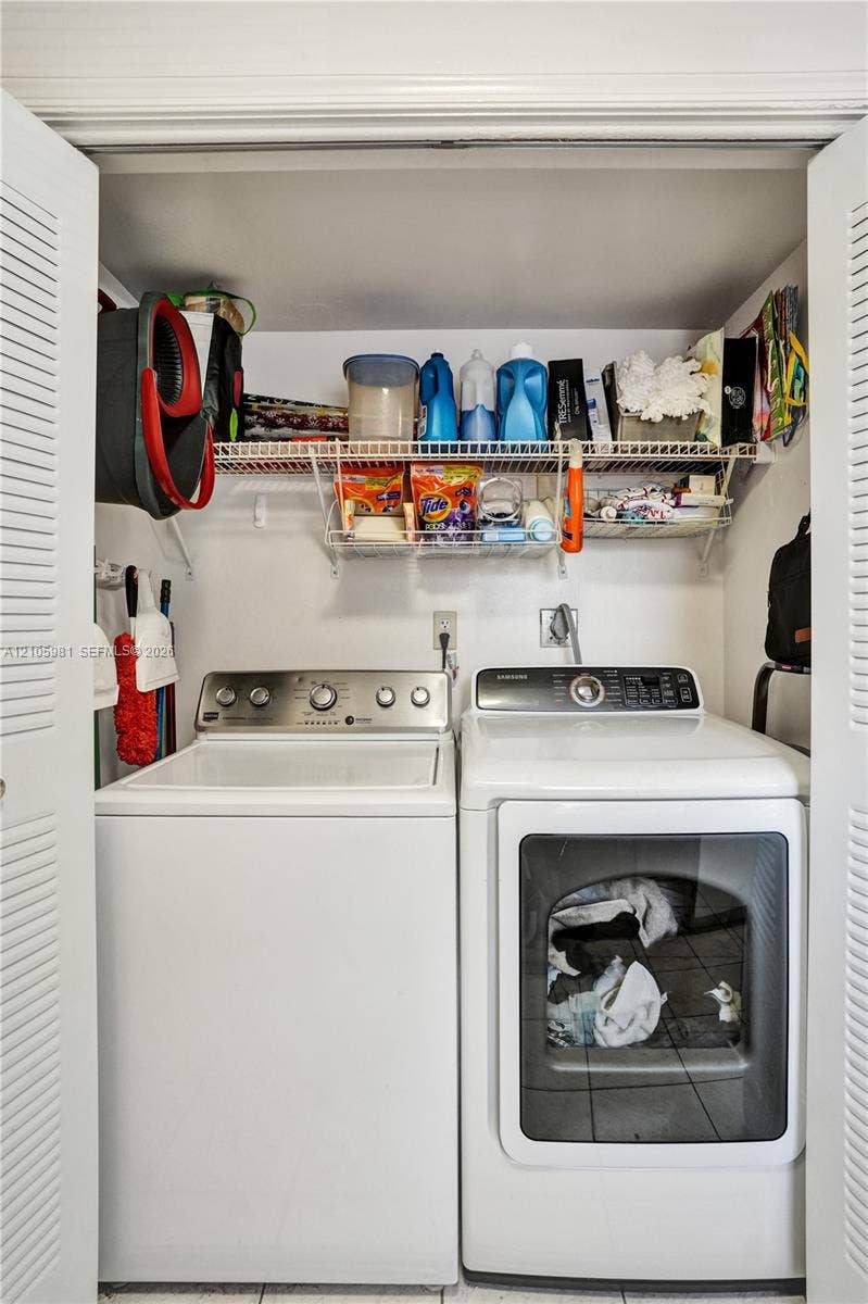 6813 NW 29th Avenue, Fort Lauderdale, Fort Lauderdale, FL 33309 Laundry area featuring louvered bi-fold closet doors, white tile flooring, and integrated wire shelving