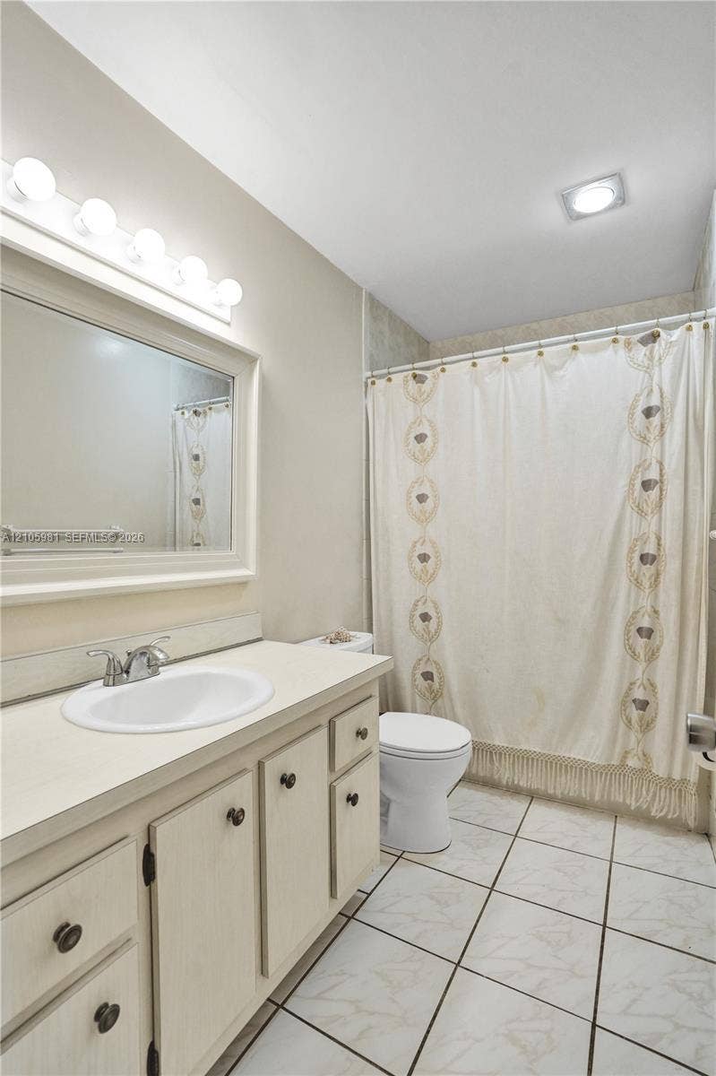6813 NW 29th Avenue, Fort Lauderdale, Fort Lauderdale, FL 33309 Bathroom featuring a vanity with integrated sink, chrome faucet, framed mirror with multi-bulb light fixture, and tile flooring