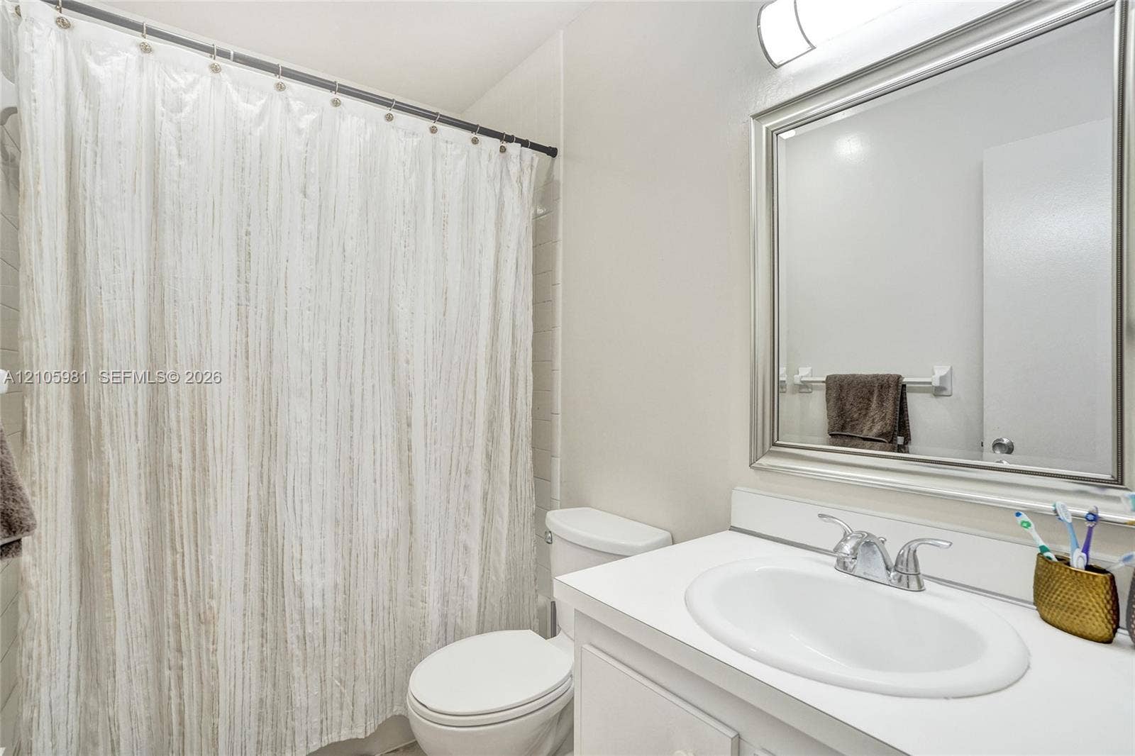 6813 NW 29th Avenue, Fort Lauderdale, Fort Lauderdale, FL 33309 Bathroom featuring a vanity with a white countertop and oval under-mount sink, polished chrome dual-handle faucet, framed wall mirror, and an overhead light fixture