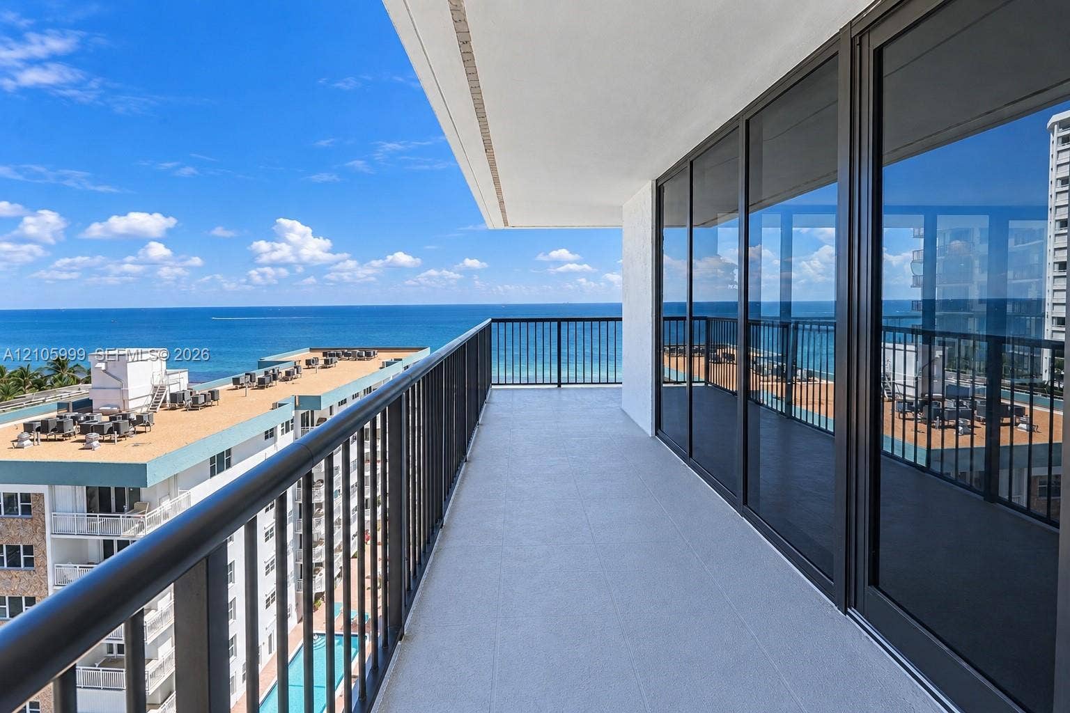 NE wraparound balcony-Covered balcony featuring a metal railing, tile flooring, and floor-to-ceiling glass sliding doors