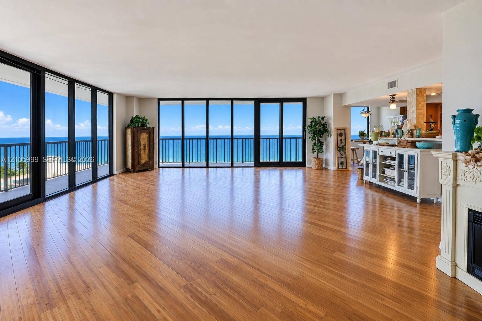 Open-concept living space featuring wood-finish flooring, floor-to-ceiling windows, and a decorative fireplace mantel
