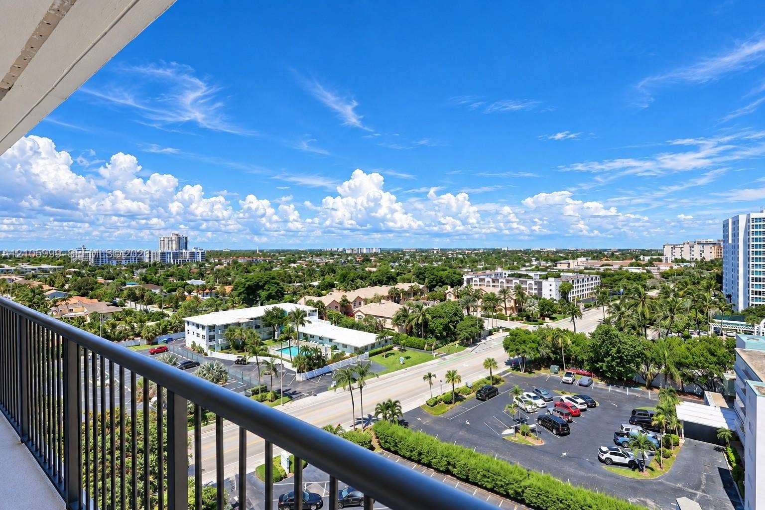 Elevated balcony featuring black metal railings and overhead soffit with expansive city and landscape scenery
