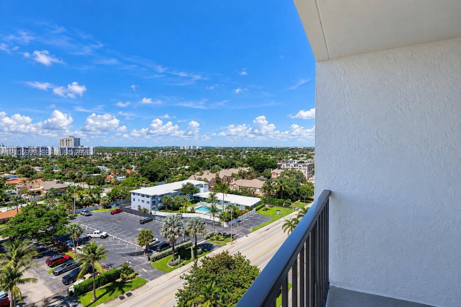 Private balcony featuring a textured stucco wall and metal railing with expansive city and landscape scenery