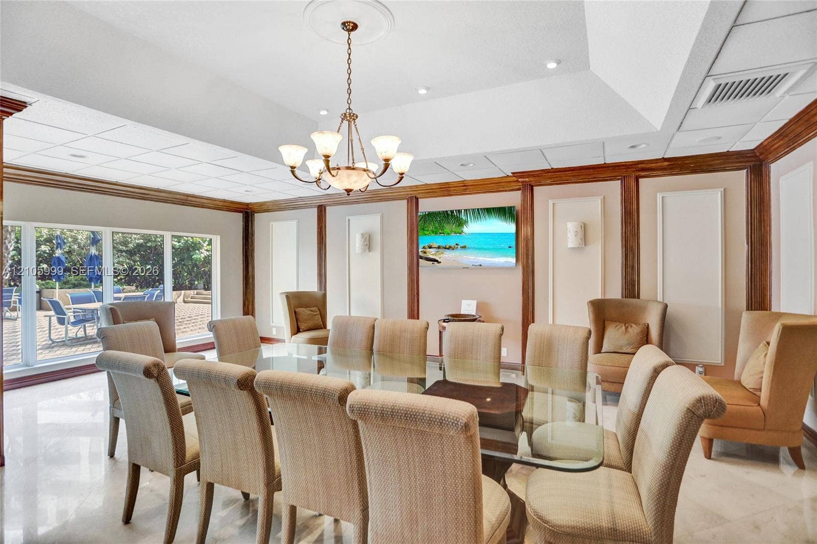 Tray ceiling featuring a central chandelier, wood-trimmed wall panels, and expansive floor-to-ceiling windows