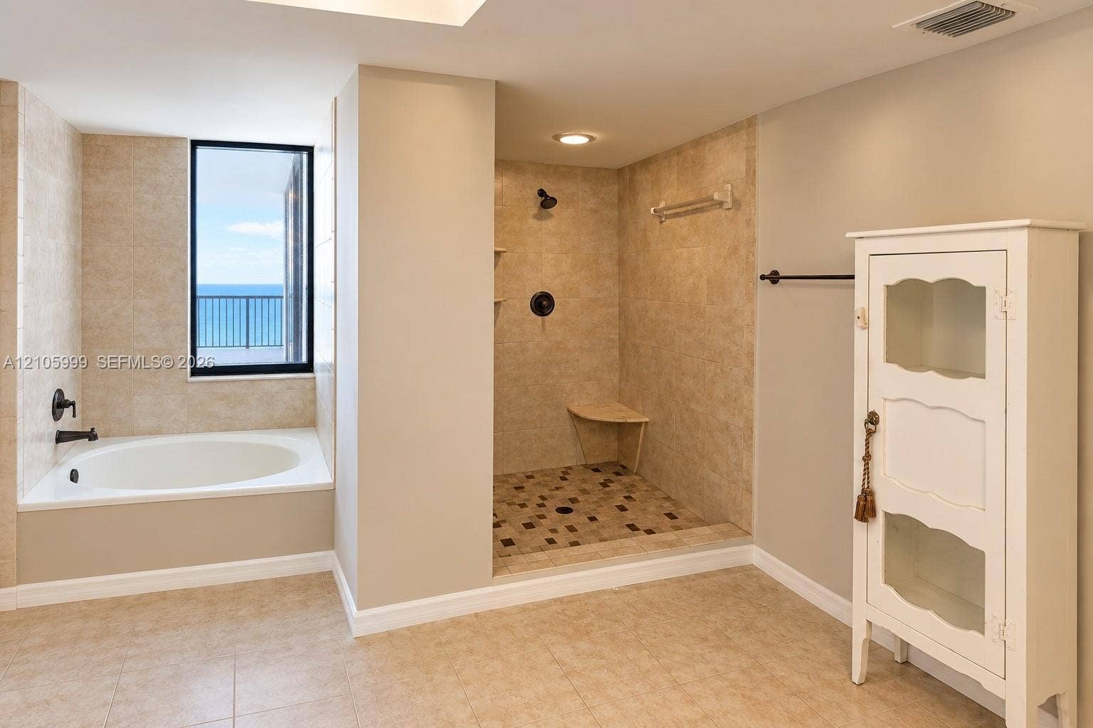 Bathroom featuring a drop-in soaking tub with a deck surround, a walk-in shower with a stone-tile floor and built-in bench, neutral wall-to-wall ceramic tile, and matte black fixtures