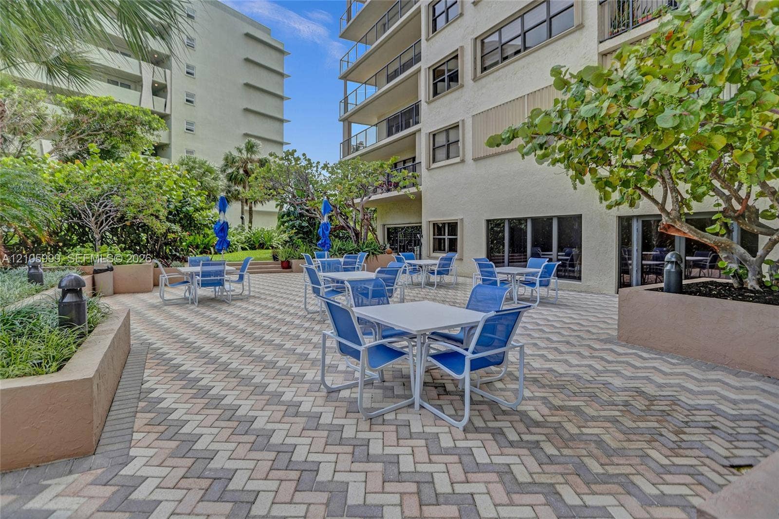 Exterior terrace featuring herringbone-patterned pavers, raised concrete planters, and mature landscaping