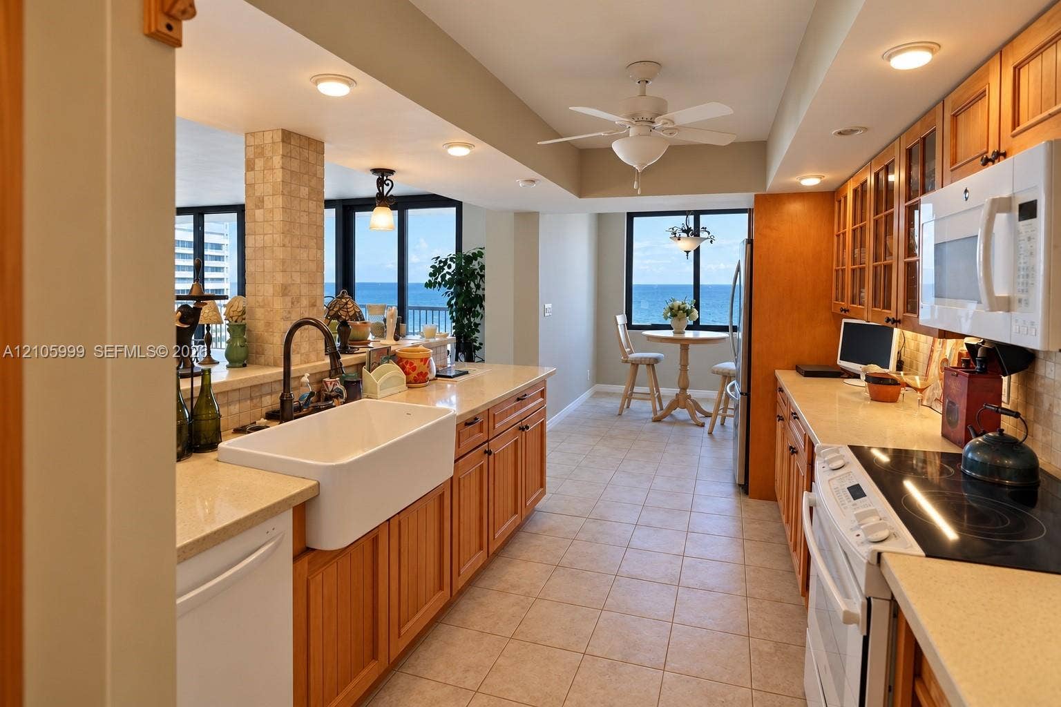 Kitchen featuring light-tone wood cabinetry, quartz countertops, a white farmhouse sink with a dark-finish faucet, tile flooring, and tile-accented structural pillar
