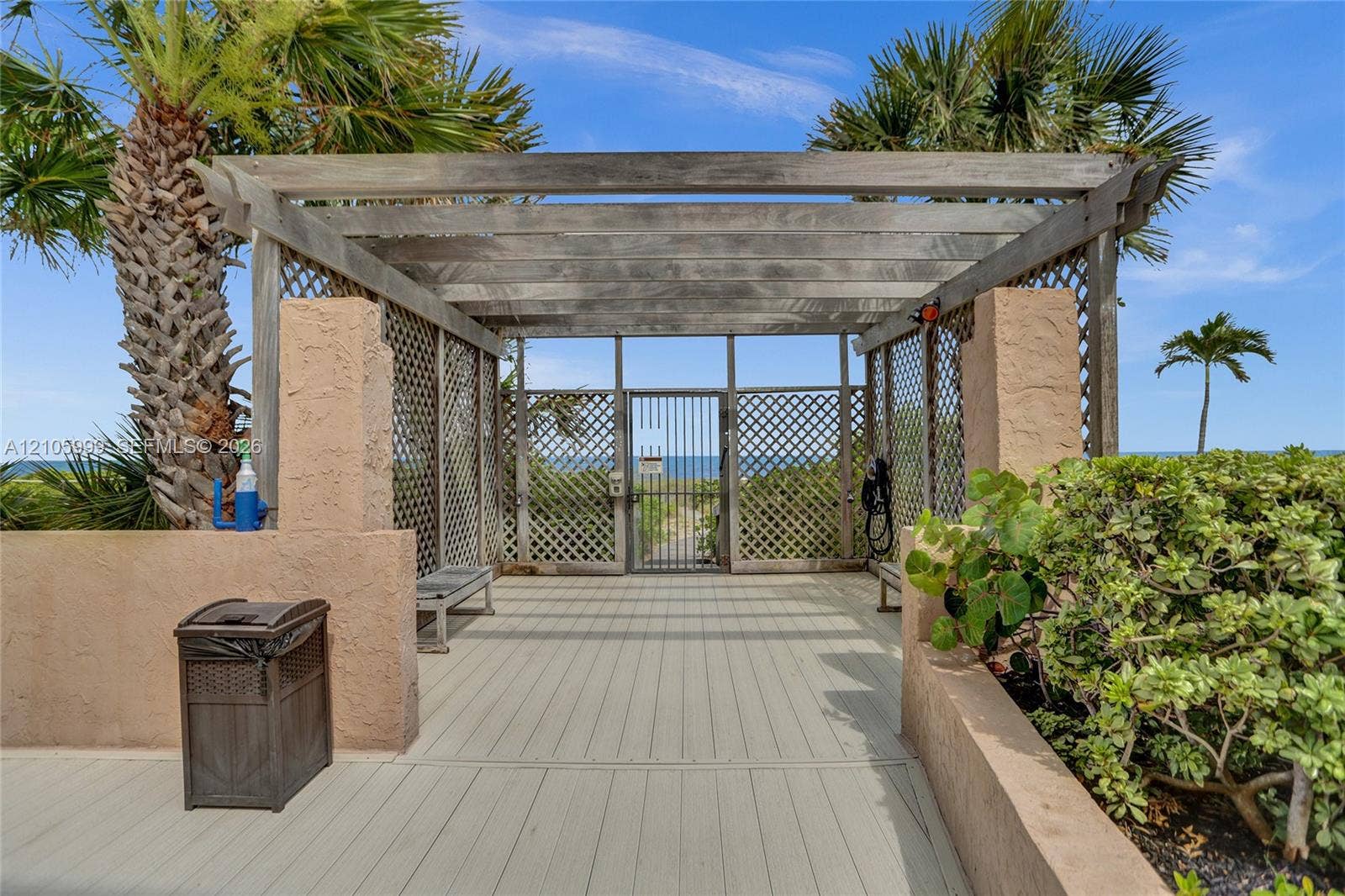 Wood-frame pergola with lattice side panels, solid surface decking, integrated benches, and gated access