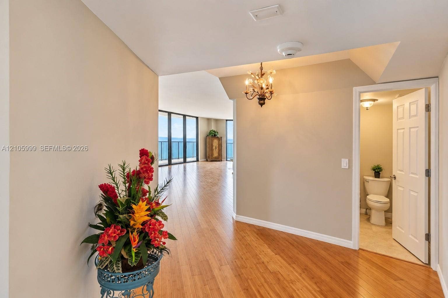 Interior entry featuring wood-finish flooring, a multi-arm metallic chandelier, and a powder room with tile flooring and a porcelain toilet