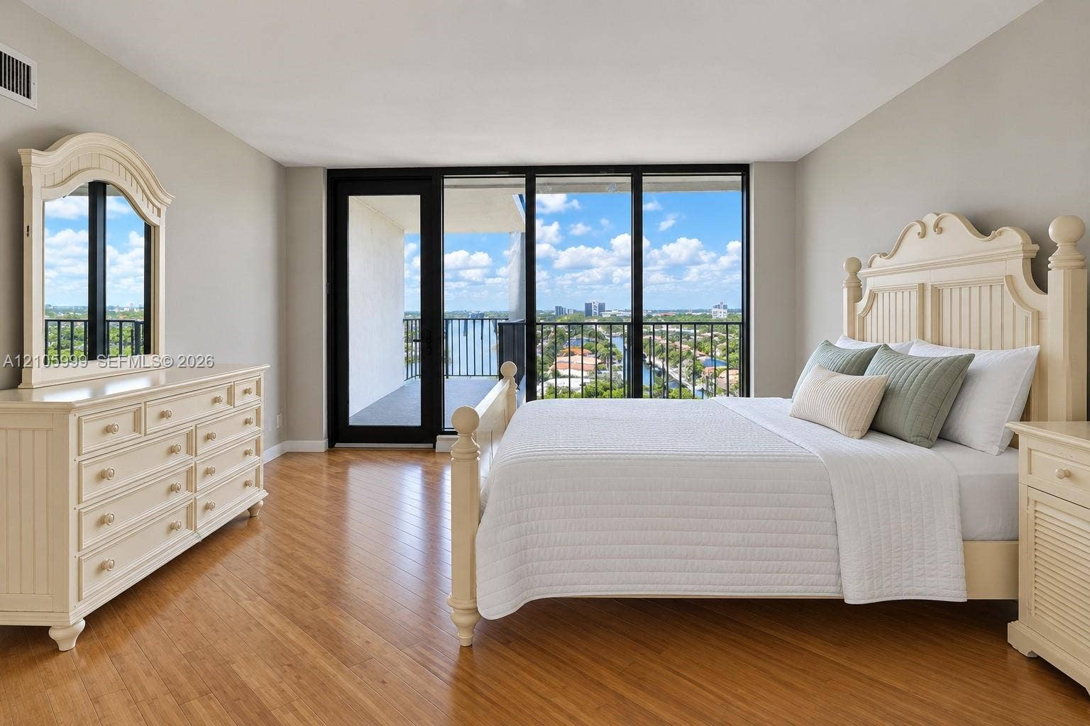 Floor-to-ceiling glass doors and windows with black frames, wood-finish flooring, and an attached exterior balcony