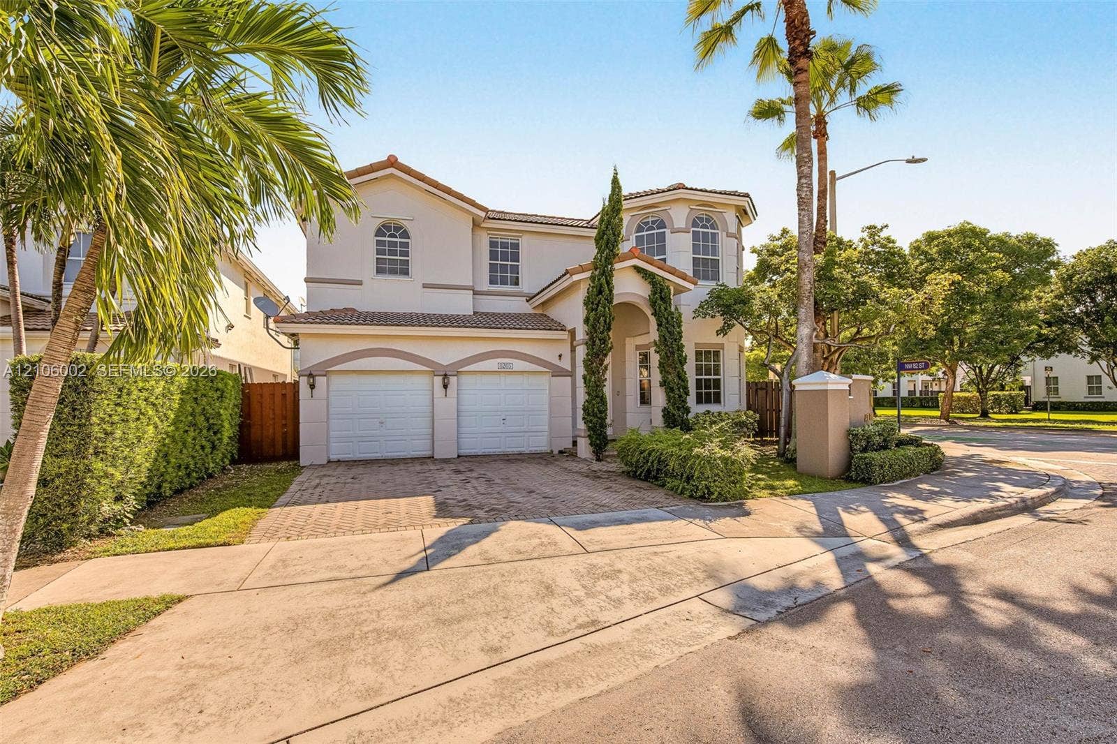 Two-story exterior featuring a stucco facade, tile roof, arched windows, and a paved driveway with two-car garage