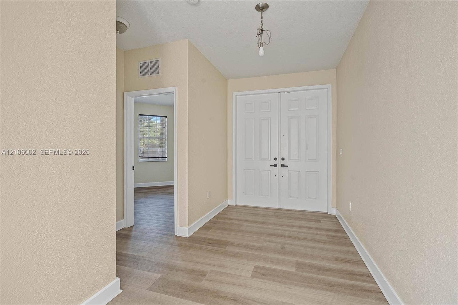 Entryway featuring double doors with metallic hardware, wood-finish flooring, and a single-pendant light fixture