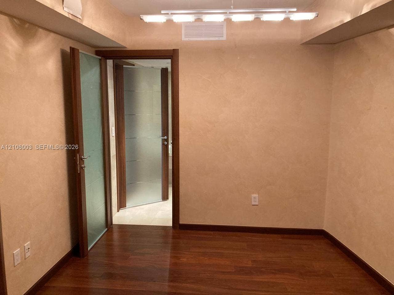 1850 S Ocean Drive, #3309, Hallandale Beach, Hallandale Beach, FL 33009 Wood-finish flooring with textured wall finishes, solid wood door frames, and frosted glass paneled doors featuring brushed metallic hardware, illuminated by a linear multi-light fixture