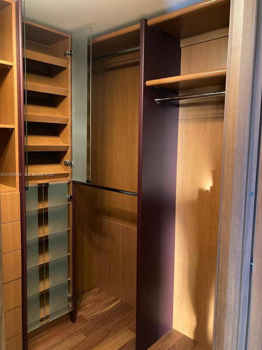 1850 S Ocean Drive, #3309, Hallandale Beach, Hallandale Beach, FL 33009 Custom closet featuring wood-finish cabinetry, built-in shelving, frosted glass door panels, integrated hanging rods, and wood-finish flooring
