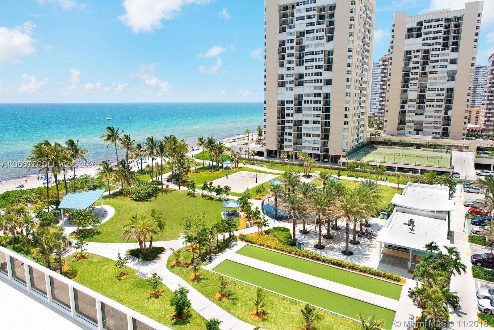 1850 S Ocean Drive, #3309, Hallandale Beach, Hallandale Beach, FL 33009 High-rise residential property featuring direct oceanfront access, landscaped green space, outdoor tennis courts, shaded pavilion areas, and palm-lined grounds