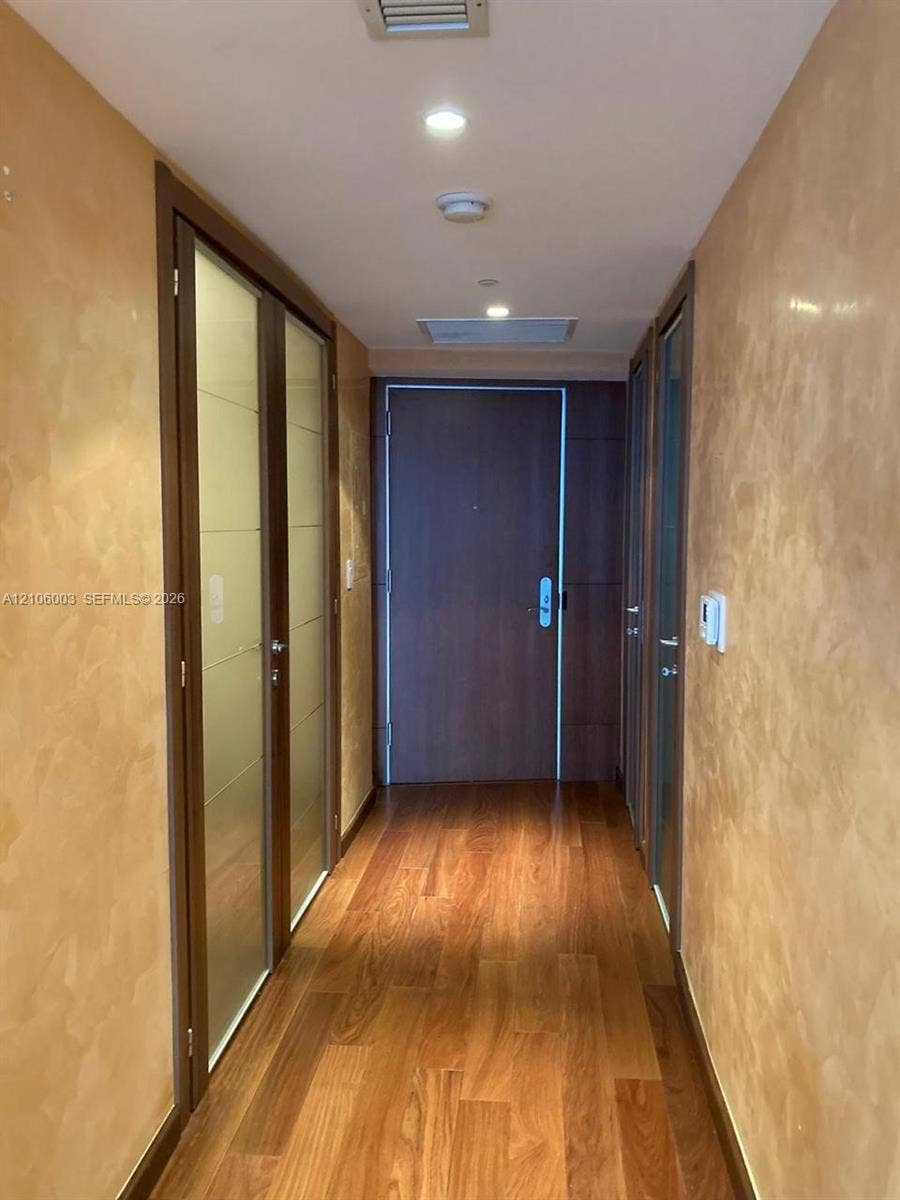 1850 S Ocean Drive, #3309, Hallandale Beach, Hallandale Beach, FL 33009 Hallway featuring textured gold-toned wall finishes, wood-finish flooring, recessed ceiling lighting, and solid-core wood doors with frosted glass inserts